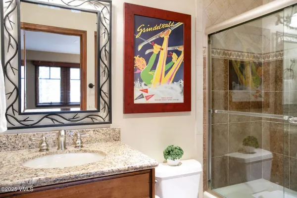 a bathroom with a granite countertop sink a toilet and a mirror