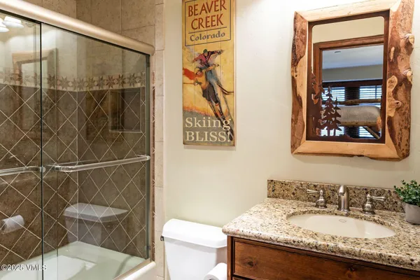 a bathroom with a granite countertop sink a toilet and a shower