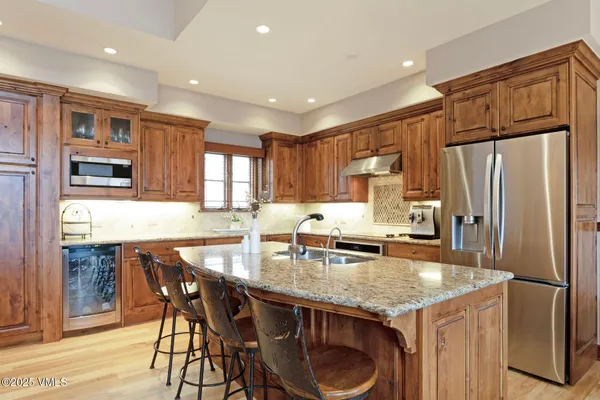 a kitchen with granite countertop kitchen island stainless steel appliances a refrigerator a stove a sink a dining table and chairs