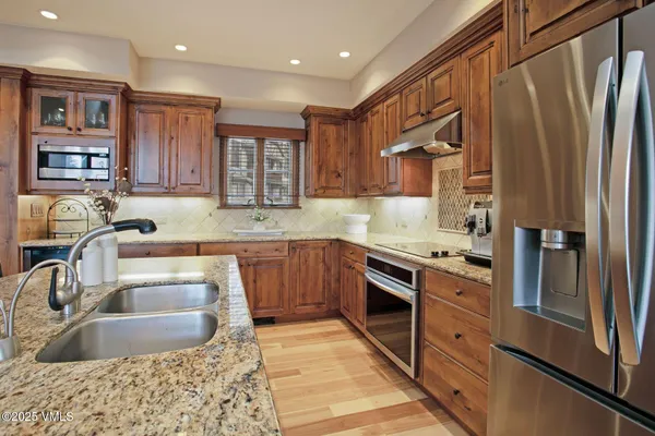 a kitchen with stainless steel appliances granite countertop a sink stove and refrigerator
