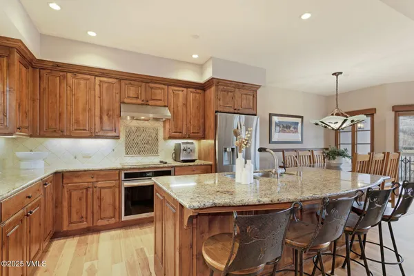 a kitchen with stainless steel appliances granite countertop a kitchen island a table and chairs in it