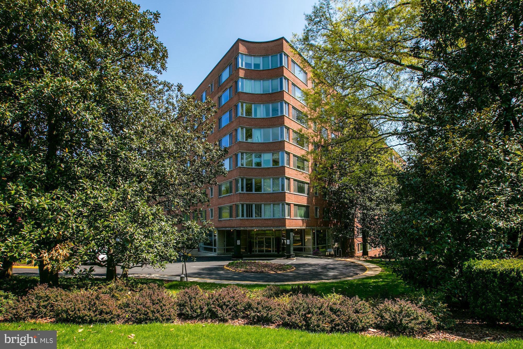 a front view of multi story residential apartment building with yard and green space