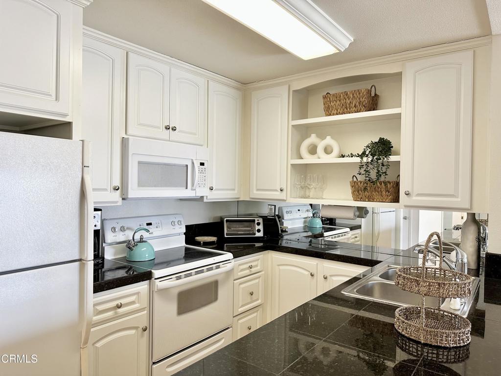 2901 Peninsula Road, Unit 347 Oxnard, CA 93035 - Photo 3 of 13 a kitchen with white cabinets and white appliances