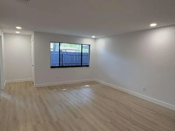 a view of an empty room with wooden floor and a window