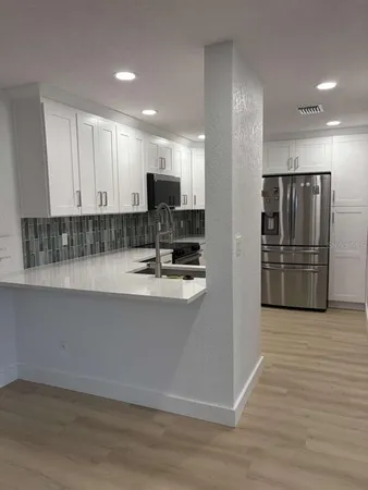 a view of kitchen with stainless steel appliances granite countertop a refrigerator and a stove top oven