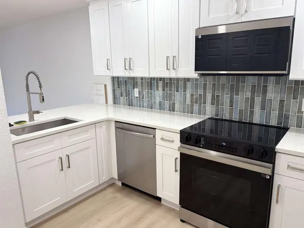 a kitchen with granite countertop white cabinets and black appliances