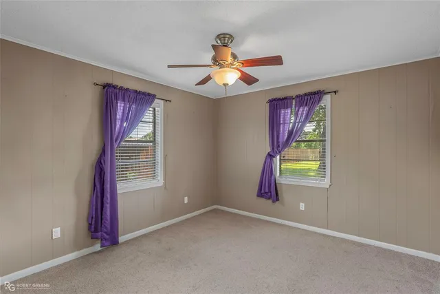 an empty room with windows and fan