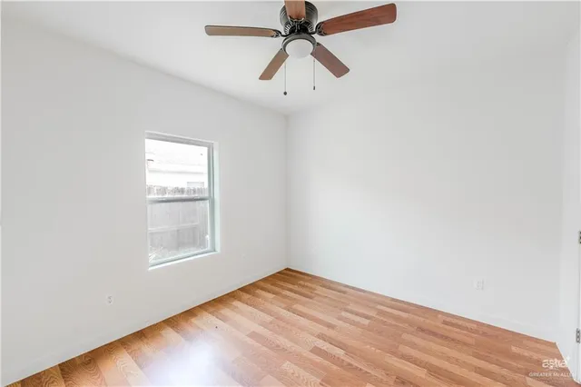 an empty room with chandelier fan and windows