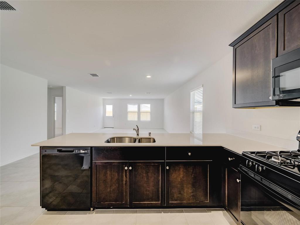 357 Sun Bluff Road Fort Worth, TX 76052 - Photo 10 of 35 Kitchen island with light-toned countertop, double basin sink, and integrated dishwasher