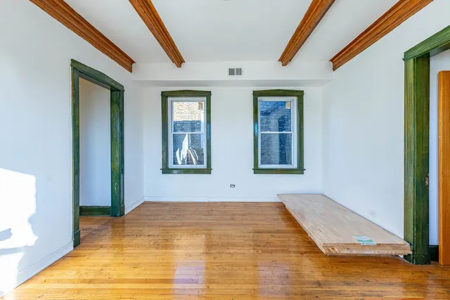 a view of an empty room with window and wooden floor