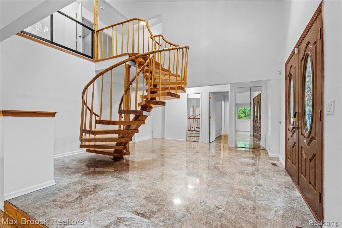 1830 Lone Pine Road Bloomfield Hills, MI 48302 - Photo 5 of 70 Grand entryway featuring a spiral staircase with wood banisters, polished marble flooring, and double entry doors with decorative glass inserts