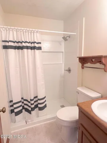 a bathroom with a granite countertop sink and a toilet