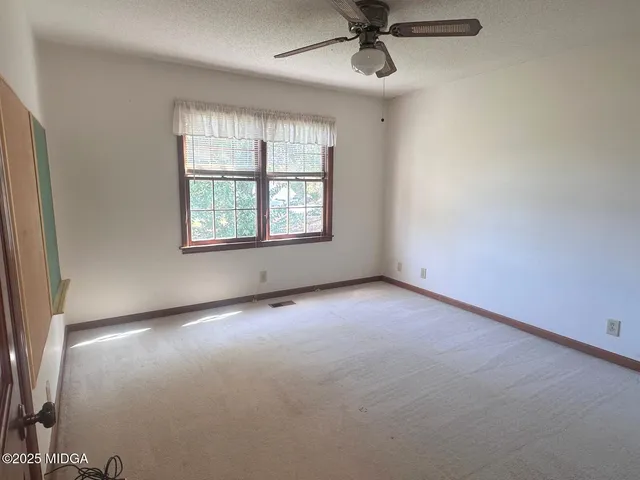 an empty room with a window and a fan