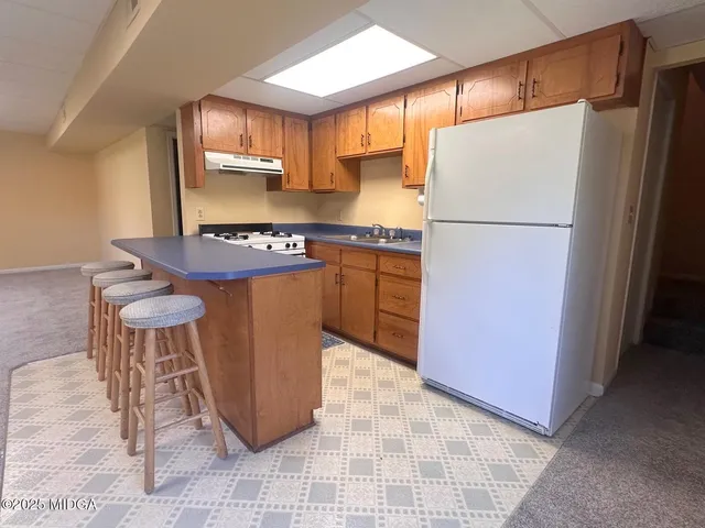 a kitchen with a refrigerator a stove a sink cabinets and a dining table