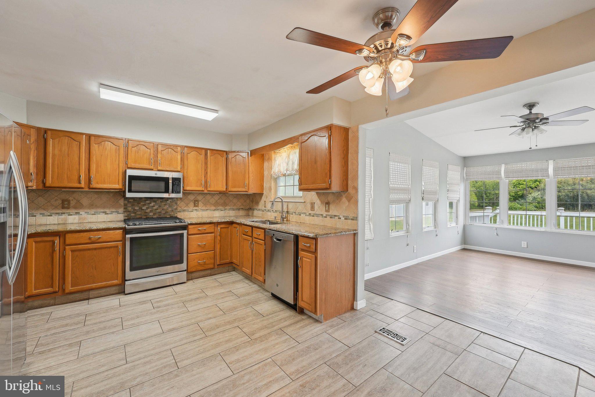 317 Clems Run Mullica Hill, NJ 08062 - Photo 9 of 33 a kitchen with stainless steel appliances granite countertop a stove top oven a sink dishwasher a dining table and chairs with wooden floor