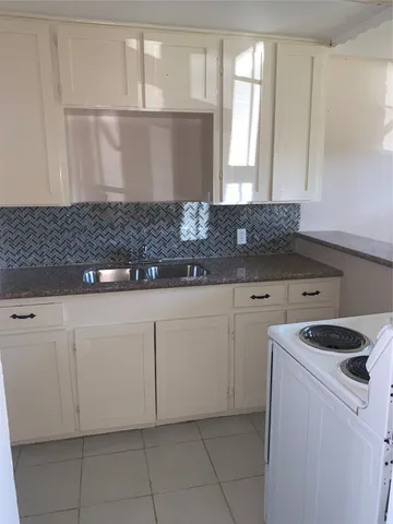 a kitchen with granite countertop white cabinets and white appliances