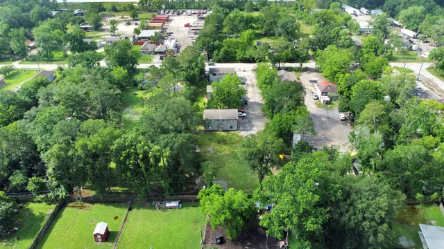 an aerial view of residential house with outdoor space and trees all around