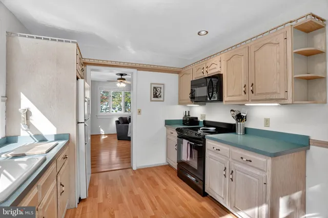 a kitchen with stainless steel appliances granite countertop a stove top oven a sink dishwasher a refrigerator and a microwave oven with wooden floor