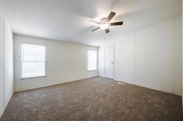 an empty room with windows and fan