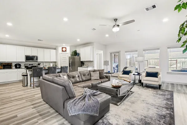 a living room with furniture kitchen view and a window