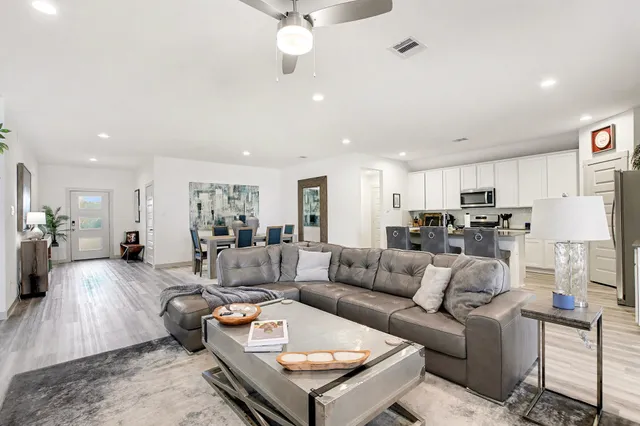 a living room with furniture kitchen view and a chandelier