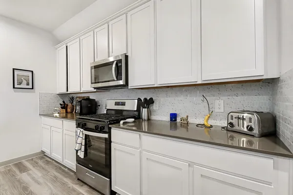 a kitchen with stainless steel appliances granite countertop white cabinets a sink and dishwasher