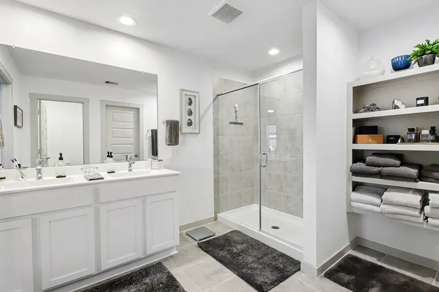 a bathroom with a double vanity sink a toilet and a shower
