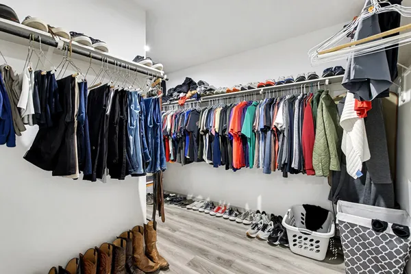 a view of walk in closet with clothes and shoes
