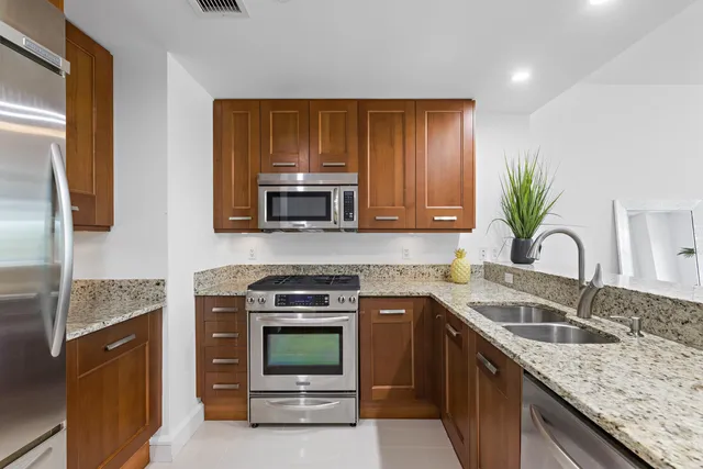 a kitchen with granite countertop a sink stainless steel appliances and cabinets