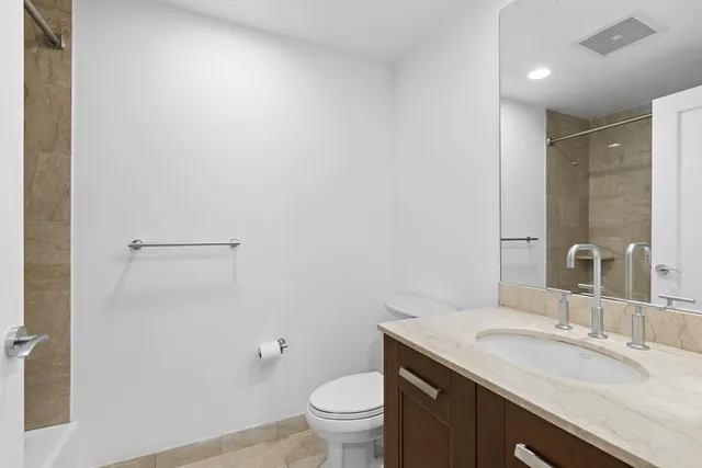 a bathroom with a granite countertop sink a toilet and a mirror