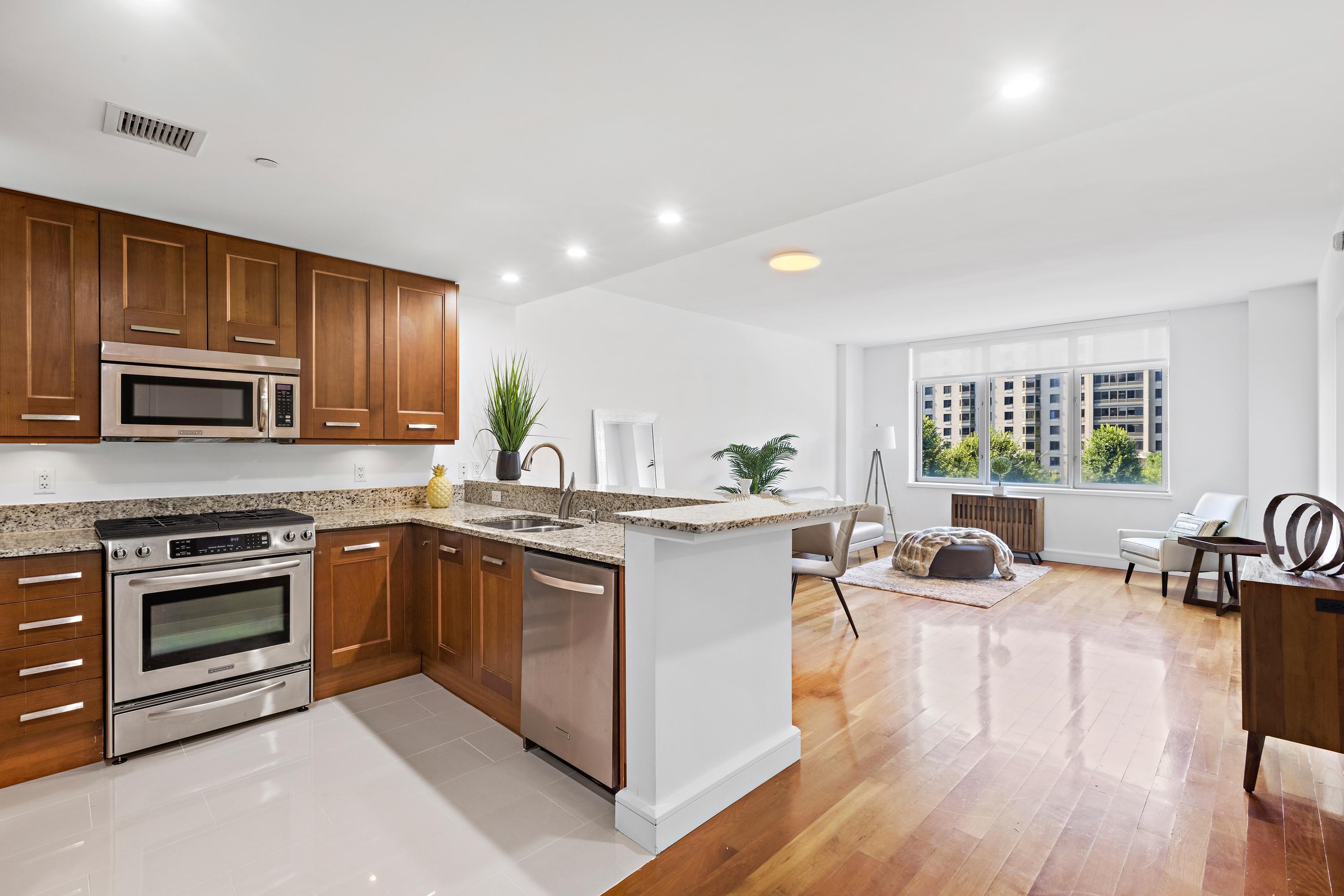 8100 River Road, Unit 510 North Bergen, NJ 07047 - Photo 3 of 25 a kitchen with stainless steel appliances granite countertop wooden cabinets a stove a sink a dining table and chairs