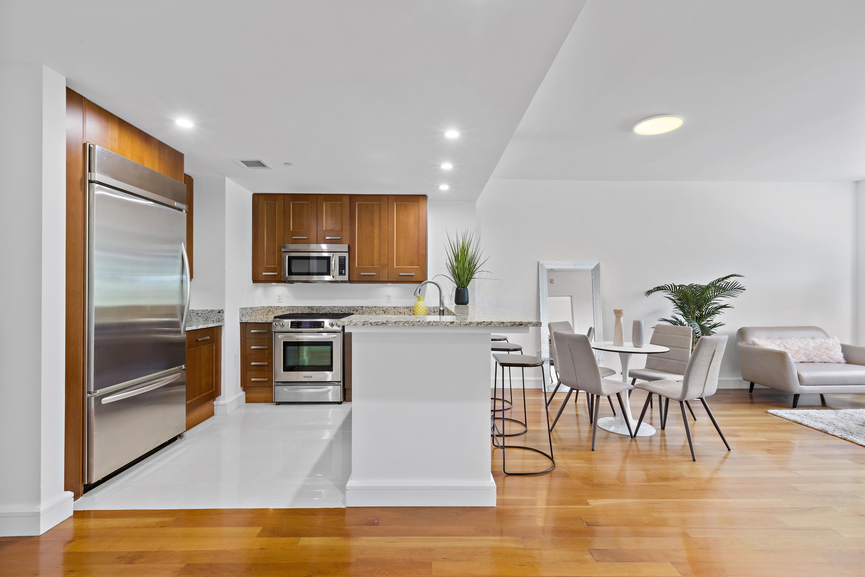 8100 River Road, Unit 510 North Bergen, NJ 07047 - Photo 9 of 25 a kitchen with stainless steel appliances granite countertop a stove top oven a sink dishwasher a dining table and chairs with wooden floor