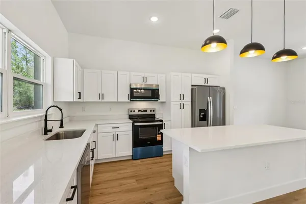 a kitchen with granite countertop a stove a sink and a refrigerator