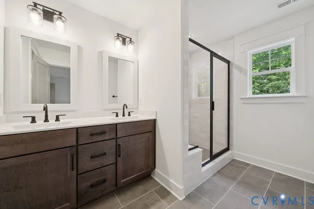 a spacious bathroom with a double vanity sink a mirror and a shower