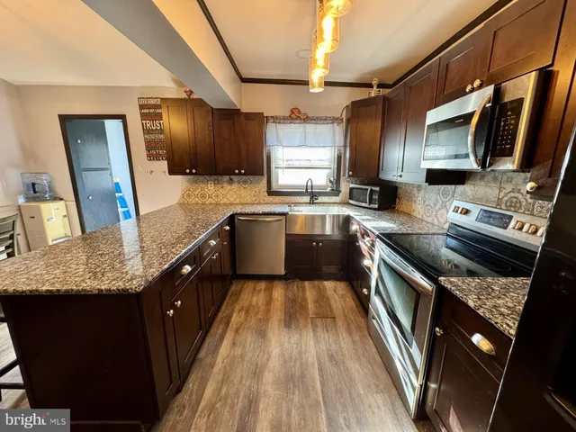 a kitchen with a granite countertop sink and refrigerator