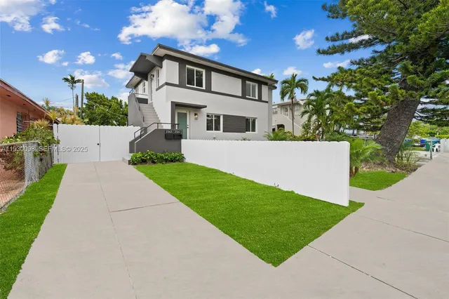 a front view of a house with a yard and potted plants