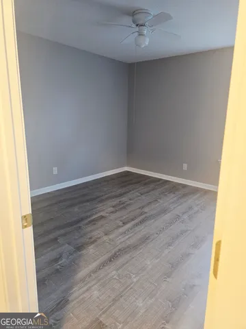 an empty room with wooden floor and fan
