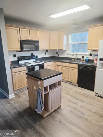 a kitchen with wooden floors and white stainless steel appliances