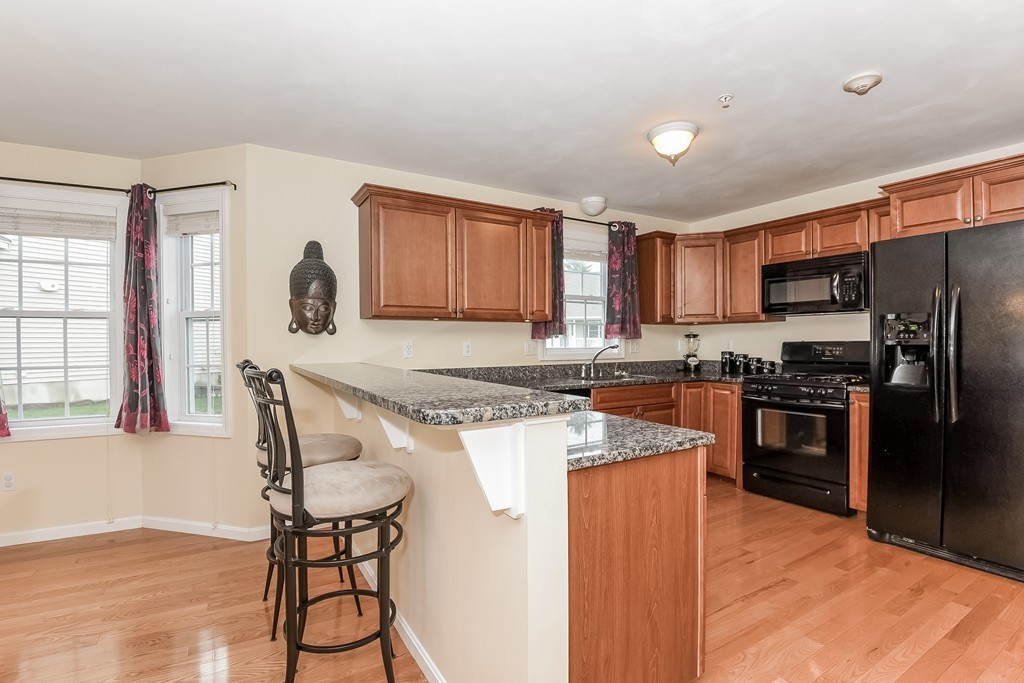 615 Nashua Road, Unit 9 Dracut, MA 01826 - Photo 5 of 30 a kitchen with stainless steel appliances granite countertop a stove top oven a sink dishwasher a refrigerator and a dining table with wooden cabinet