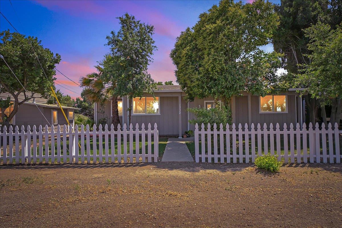 a view of a house with a small yard and wooden fence