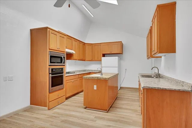 a kitchen with granite countertop a sink cabinets and wooden floor