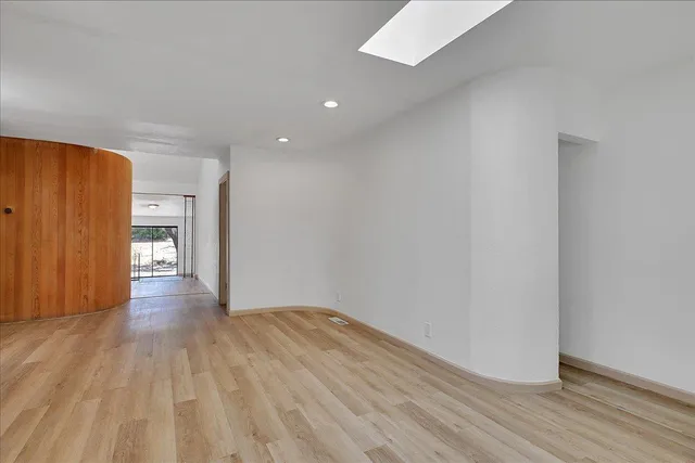 a view of an empty room with wooden floor and closet