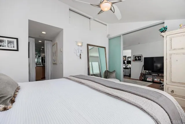a bedroom with a bed a large mirror and a flat tv screen on dresser