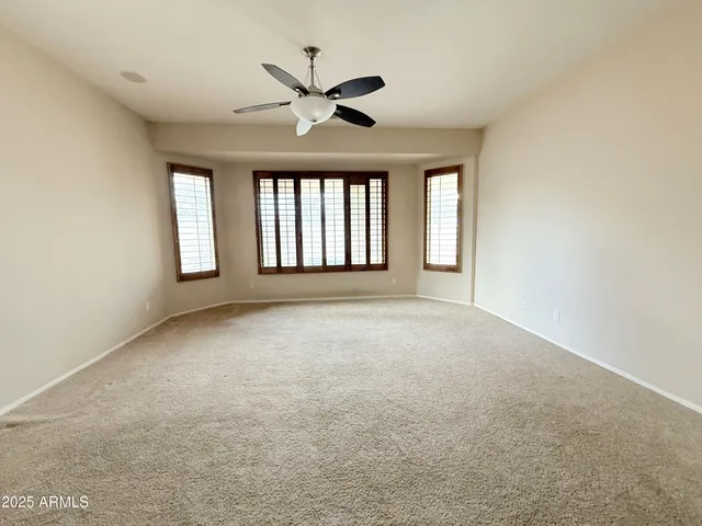 an empty room with windows and ceiling fan