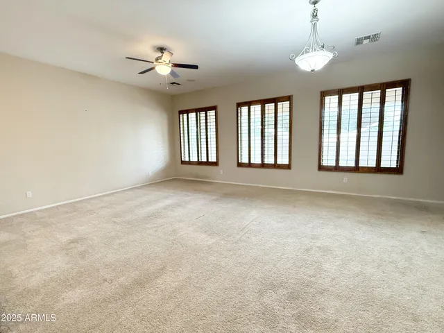 an empty room with windows and chandelier fan