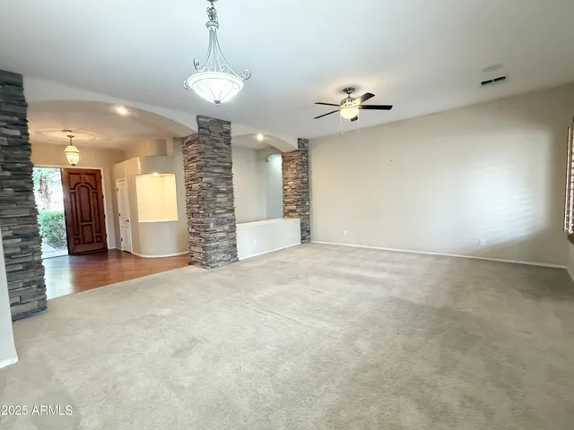 an empty room with a chandelier fan and windows