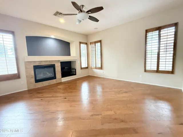 a view of an empty room with a fireplace and wooden floor