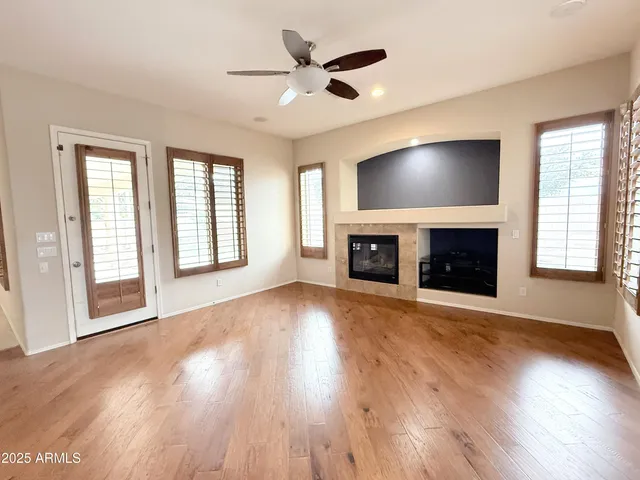 an empty room with windows fireplace and wooden floor