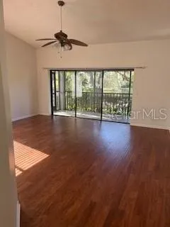 a view of an empty room with wooden floor a ceiling fan and a fireplace