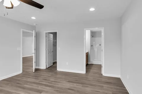 a view of an empty room with wooden floor and closet